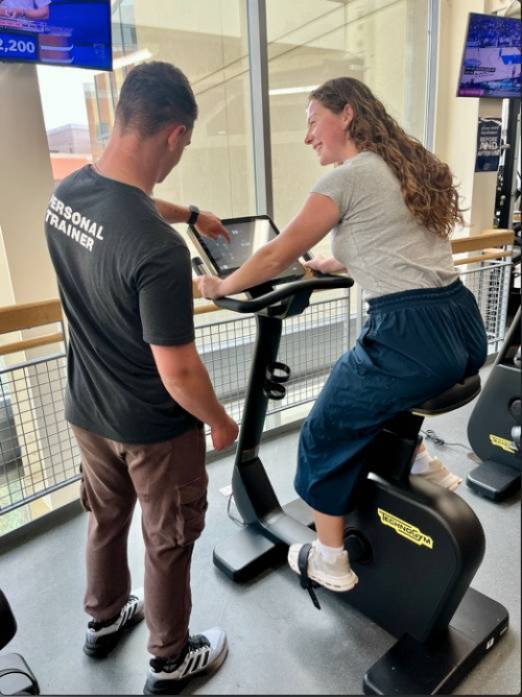 Trainer coaching client on cycle.